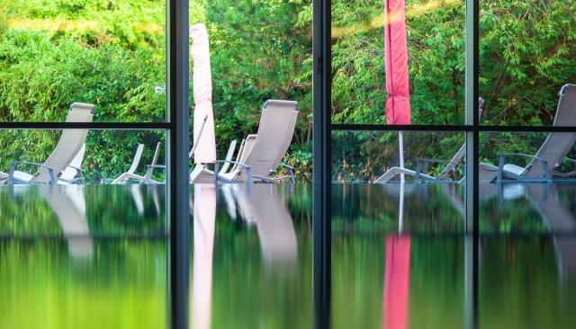 Liegen im Spa-Bereich spiegeln sich auf Wasseroberfläche des Pools